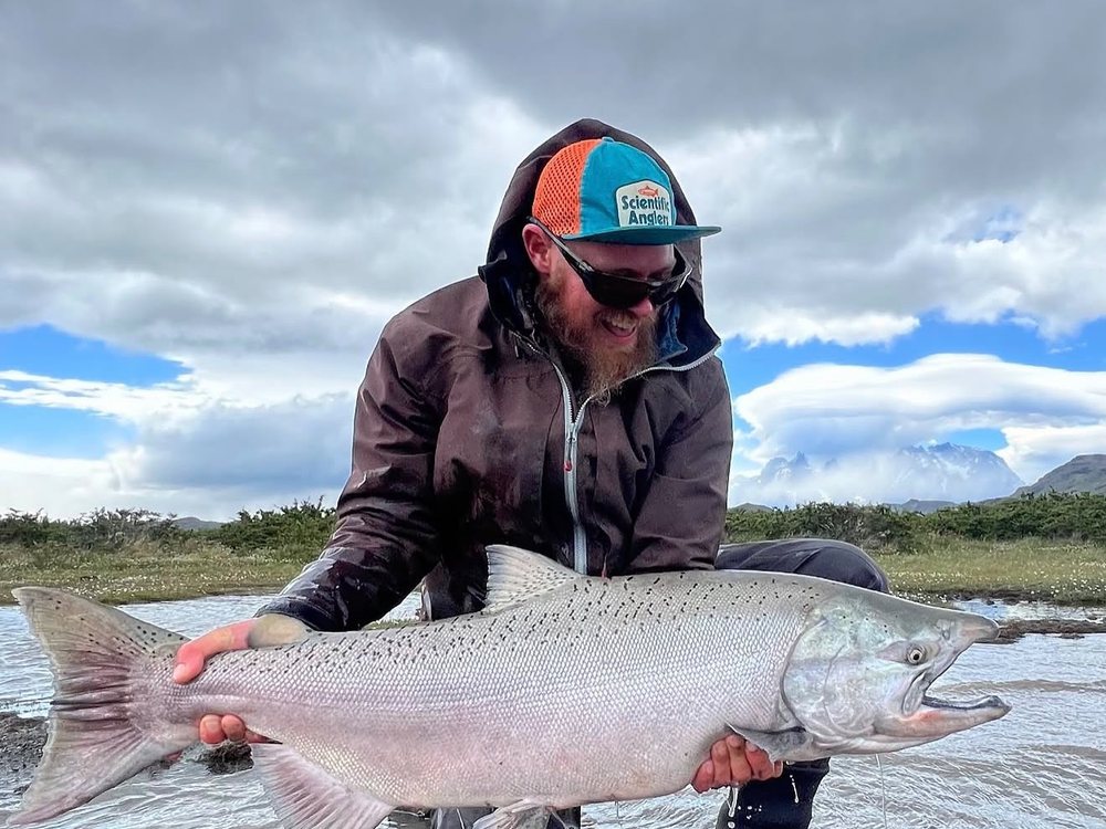 Martín holding a king salmon below the Paine massif